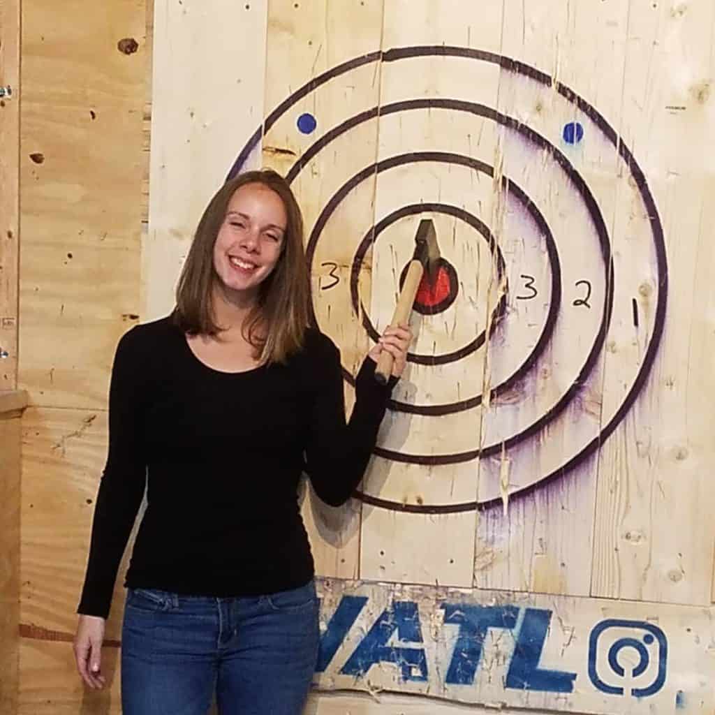 woman holding her axe stuck in a target bullseye